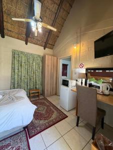 a bedroom with a bed and a table and a kitchen at SETLHARE GUEST LODGE in Ganyesa