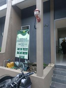 a motorcycle parked in front of a building with a sign at Herald homestay wonosobo in Wonosobo