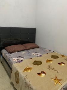 a bed with a comforter with shells on it at Herald homestay wonosobo in Wonosobo