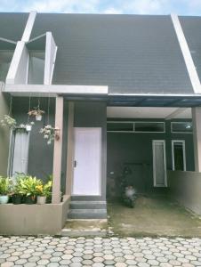a green house with a white door and plants at Herald homestay wonosobo in Wonosobo