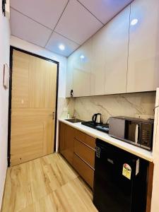 a kitchen with a sink and a microwave and a door at Urban Luxury Studio Apartment in Greater Noida