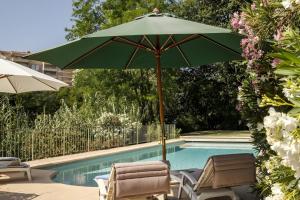 a green umbrella and chairs next to a swimming pool at Villa Marie in Vence