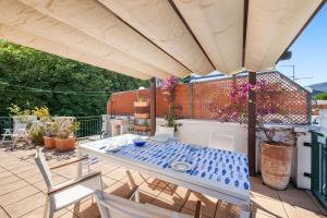 a patio with a table and chairs under a large umbrella at Lisa's Stylish Top Floor Flat & Double Pool in Pietra Ligure