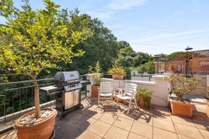 a patio with a grill and a tree on a balcony at Lisa's Stylish Top Floor Flat & Double Pool in Pietra Ligure