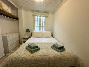 a bedroom with a bed with two green towels on it at Achladies Cottages in Achladies