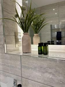 a bathroom counter with two vases and a mirror at 6 Aviv Place in Addlestone