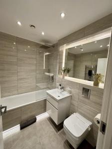 a bathroom with a toilet and a sink and a tub at 6 Aviv Place in Addlestone