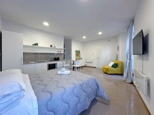 a bedroom with a large bed and a kitchen at BBkey Corte San Daniele in San Daniele del Friuli