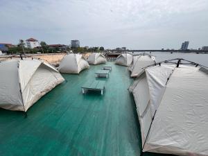 a row of tents in the water with tables and benches at AHHA Floatel Kampot in Kampot