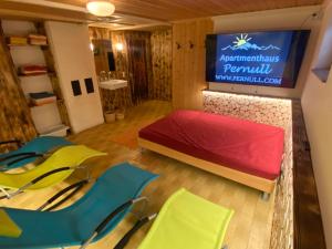 a room with a bed and a tv and chairs at Apartmenthaus Pernull in Tröpolach