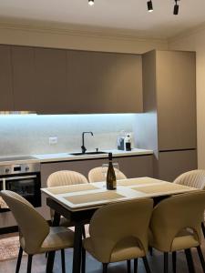 a kitchen with a table with chairs and a bottle of wine at Olive Tree in Tirana
