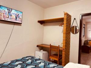 a bedroom with a bed and a tv on the wall at Rochas - Suíte no Centro de Viçosa do Ceará in Viçosa do Ceará
