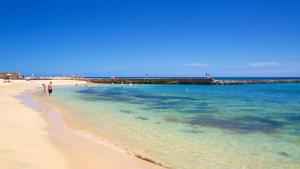 a group of people walking on the beach at Casita Moritz - Luxury - 1 min to the Beach By Lanzarote Vacation Homes in Costa Teguise