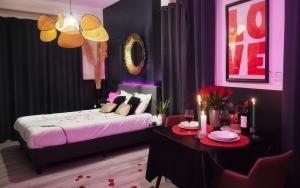 a bedroom with a bed and a table with a tableasteryasteryasteryasteryastery at Suite Passion - Jacuzzi privé - Table massage in Saint-Étienne