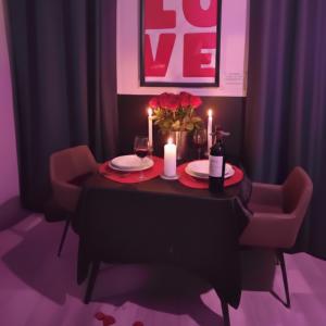 a table with two candles and a vase of flowers on it at Suite Passion - Jacuzzi privé - Table massage in Saint-Étienne