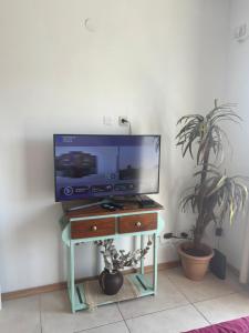a tv on a stand with a table with a tv at Experiencia Brown a Mtros Sanatorio Juncal in Temperley
