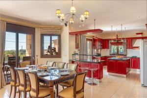 a kitchen with red cabinets and a table and chairs at Villa Omega Kefalonia in Karavádhos