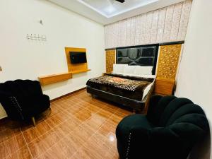 a bedroom with a bed and two chairs in it at Hotel DE Smart Multan in Multan