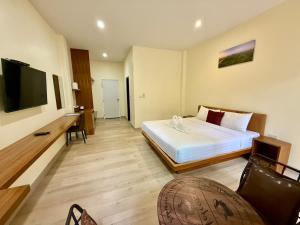 a bedroom with a bed and a desk and a television at Farinda Resort in Phangnga