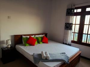 a bedroom with a bed with green and red pillows at Mountain Bliss Villa Peradeniya in Peradeniya