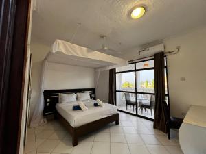 a bedroom with a bed and a view of a balcony at Becky Homes Diani Beach - 2BR with AC & Pool in Diani Beach +23 photos