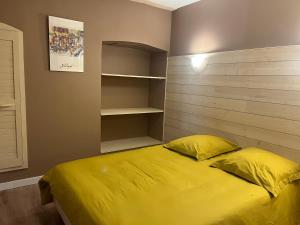 a bedroom with a yellow bed and shelves at Apartment in Mostuejouls in Mostuéjouls