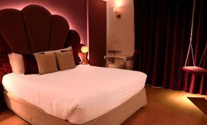 a bedroom with a large white bed with a large headboard at Paris j'Adore Hotel & Spa in Paris