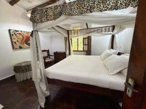 a bedroom with a white bed with a leopard print canopy at Nyumba Malaika in Malindi