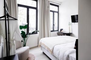 a white bedroom with a bed and windows at ROMY ANTWERP Sint-Jansvliet in Antwerp