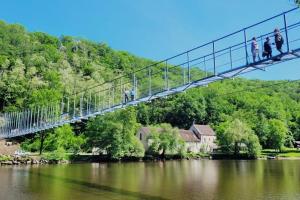 people walking across a suspension bridge over a river at Villa le Roche du Ris - 10-12 personnes in Baraize +40 photos