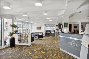 a lobby of a library with a reception desk and chairs at Hotel Pinenhus in Glyngøre