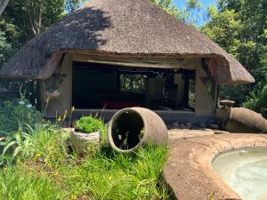 a thatch roof hut with a swimming pool at Cave view Cottages in Muldersdrift