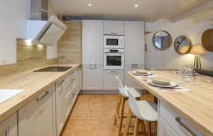 a kitchen with white cabinets and a table and chairs at Maison Proche Port Et Plage in Saint-Vaast-la-Hougue