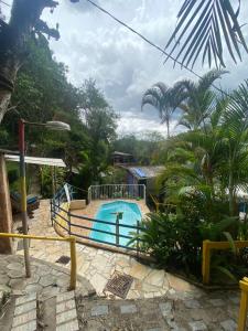 a pool in a garden with a fence around it at Pousada e Hostel Cantinho dos Chalés in São Luiz do Paraitinga