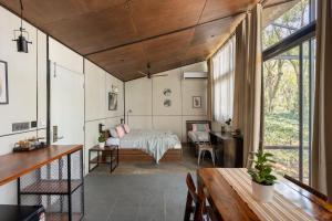 a room with a bed and a desk and a table at Cove by Raho - Nestled Away Retreat in Siddapur +53 photos
