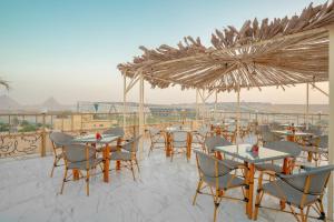 a restaurant with tables and chairs and umbrellas at Sunshine Pyramids& Grand Museum View in Cairo