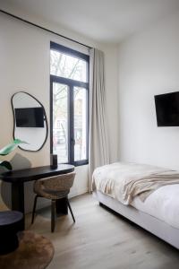 a bedroom with a bed and a desk with a mirror at ROMY ANTWERP Sint-Jansvliet in Antwerp
