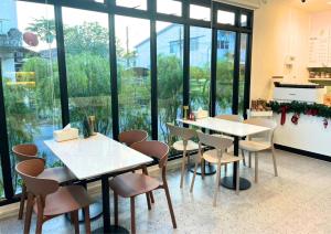 a restaurant with tables and chairs and large windows at Mani Ranong Hotel in Ranong