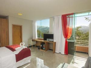 a bedroom with a bed and a desk and a window at Hotel do Papai Noel in Penedo