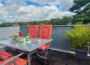 a patio table with orange chairs on a balcony at Hillis Ferienwohnung Saarland in Sankt Ingbert