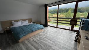 a bedroom with a bed and a large window at Pensiunea Panoramic in Stațiunea Climaterică Sâmbăta