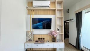 a living room with a tv on a wall at Legacy pool villa in Ban Chong Phli