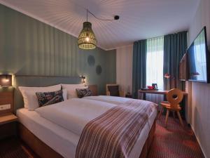 a hotel room with a large bed and a television at Classik Hotel Martinshof, Messe München in Munich