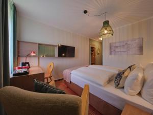 a hotel room with a bed and a chair at Classik Hotel Martinshof, Messe München in Munich