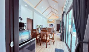 a dining room with a tv and a dining table at Legacy pool villa in Ban Chong Phli