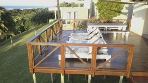 a deck with white chairs on top of a house at Waves End Holiday Home in Southbroom