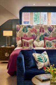 a bedroom with a bed and a blue couch at Langshott Manor - Luxury Hotel Gatwick in Horley
