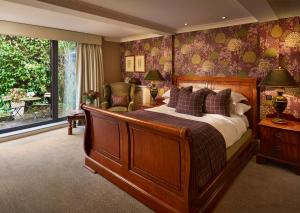 a bedroom with a large wooden bed and a window at Langshott Manor - Luxury Hotel Gatwick in Horley +116 photos