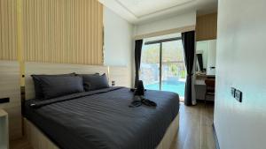 a bedroom with a bed with a cat sitting on it at Legacy pool villa in Ban Chong Phli
