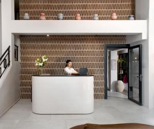 a man sitting at a white counter in a lobby at Anise Aluma Athens, Tapestry Collection by Hilton in Athens +135 photos